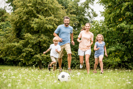 Family playing soccer in summer with their childrenの写真素材