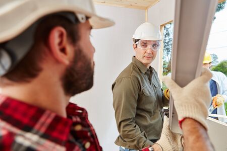 Mechanic team working at construction site installing windowの写真素材