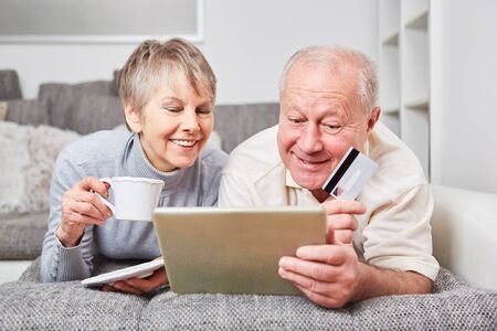 Seniors as couple on the couch listen to music onlineの写真素材