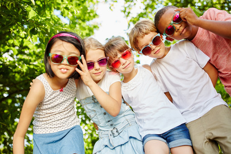Children as friends in cool interracial team together at the park in summerの写真素材