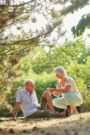 Woman helps senior man with knee injury in summer in the natureの写真素材