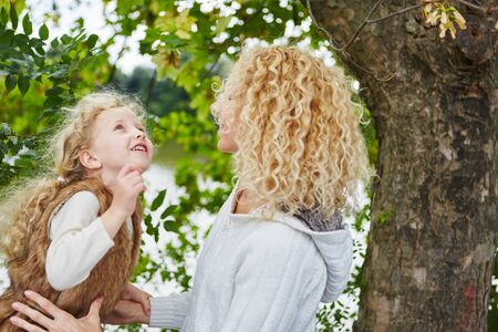 Mother and daugther talking and playing at the park in autumnの写真素材