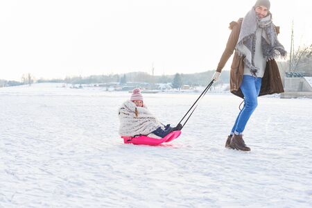 Father pulls child with sled in winter on the snowの写真素材