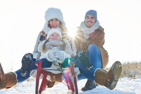 Family with child drive toboggan or sled in the snow and have funの写真素材
