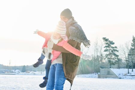 Father and daughter play together in winter in the snow