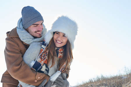 Happy couple in love in winter and man hugs girlfriend
