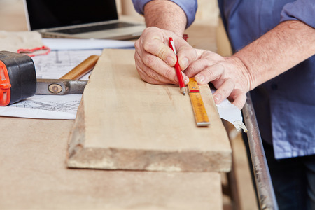 Carpenter measuring wood board with pen and rulerの写真素材