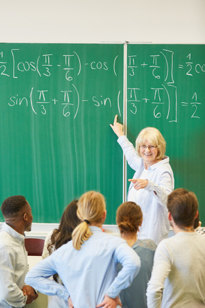 Woman as math teacher in school explains formula to studentsの写真素材
