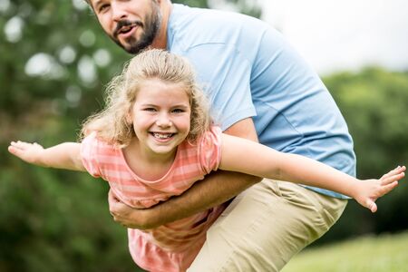 Girl playing to fly with father as a family with joyの写真素材