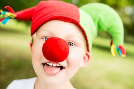 Happy boy with red nose having fun at carnivalの写真素材