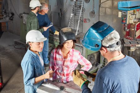 Two women in welder apprenticeship learning during metallurgy lessonの写真素材
