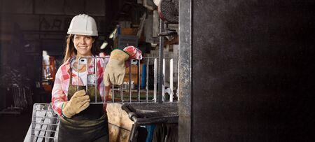 Young woman as metalworker holding mold in metallurgy workshopの写真素材