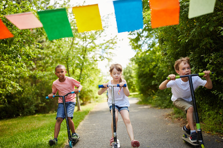 Children's fun race in the park with scooter in summerの写真素材