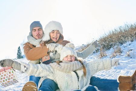 Family having fun with toboggan on the snow in winter