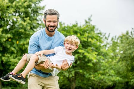 Father carrying son and playing together laughing and having fun