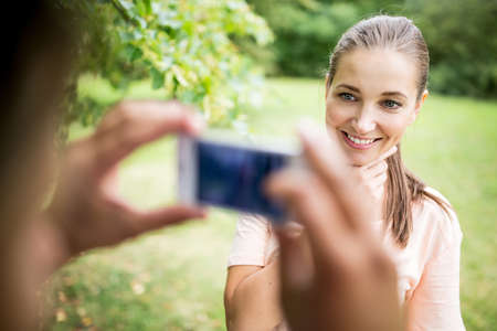 Man taking photograph of woman with smartphone in summer in the nature
