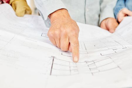 Floorplan and architect pointing and making decisions about building construction