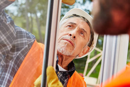 Senior competent window fitter assembles and modernizes new windowの写真素材