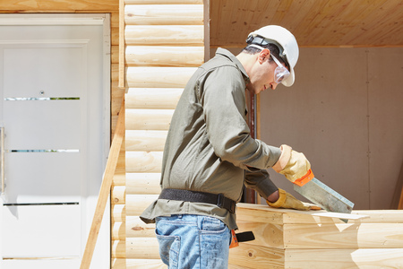 Craftsman as carpenter cutting wood with saw