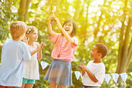 Asian girl with cup cheers as winner at award ceremony in summerの写真素材