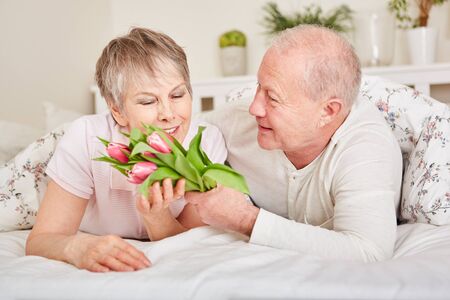 Senior man surprises wife with flowers for valentine dayの写真素材