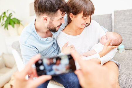 Happy parents and their little baby are photographed with the smartphone