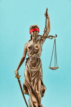 Justitia bronze sculpture as law and justice concept in front of a blue backgroundの写真素材
