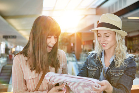 Two young women are shopping clothes together at retail mallの写真素材