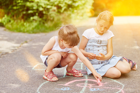 Girls paint hopscotch game with chalk at park の写真素材