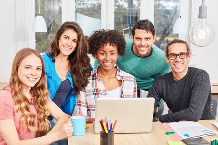 Group students as successful internet start-up team with laptop computer