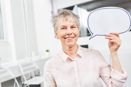 Senior business woman with speech bubble as communication conceptの写真素材