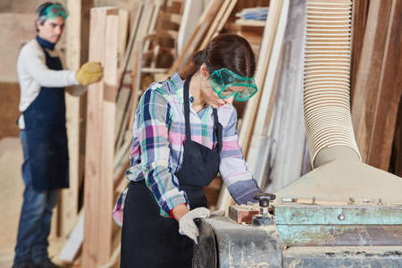 Woman as carpenter working with planing machineの写真素材
