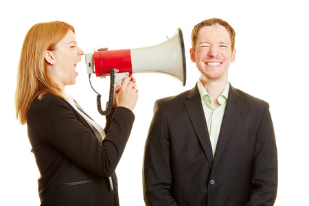 Woman screaming to a man with a megaphone very loudの写真素材