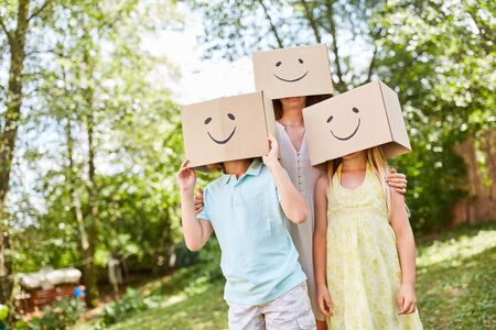 Children play with funny painted cardboard boxes on their heads in the gardenの写真素材