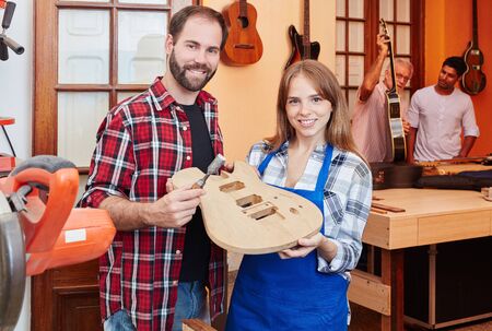 Proud luithier and guitar maker apprentice hold guitar in constructionの写真素材