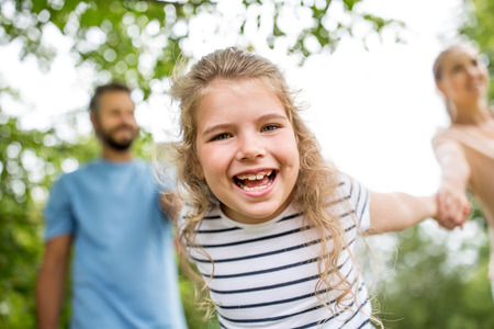 Happy girl with her family laughing and playing in the parkの写真素材