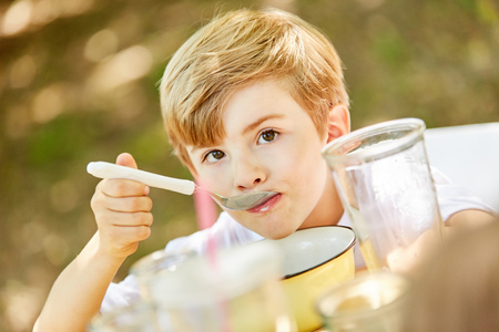 Boy is eating healthy cereal in the morning for breakfast in kindergarten or at homeの写真素材