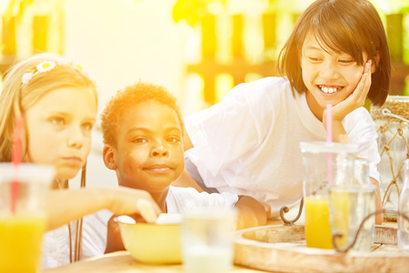 Happy kids eating breakfast cereal together at summer campの写真素材
