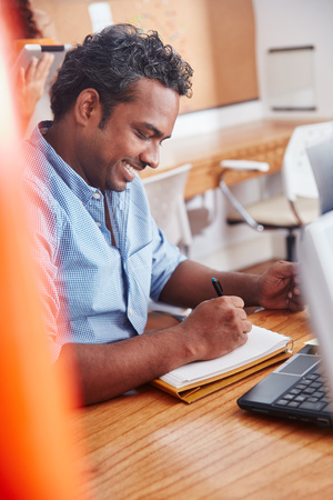 Indian man working in office and taking notes for planningの写真素材