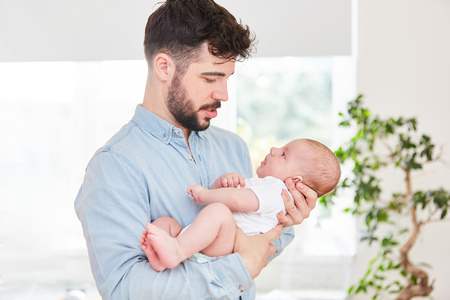 Man as a happy father lovingly looks at his newborn baby