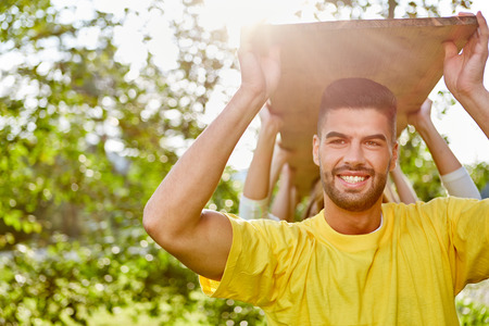 Young sportsman carries a wooden board together with his team during team trainingの写真素材