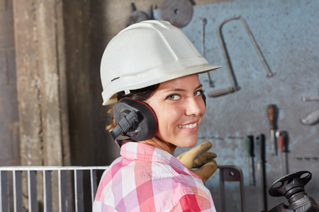 Woman as worker apprentice with ear protection and hardhat as labor safety conceptの写真素材