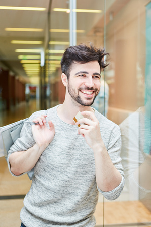 Happy young man with credit card in shopping mall while shoppingの写真素材