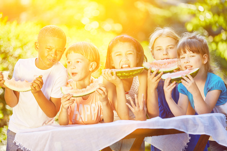 International group of children eating fruit in summer in gardenの写真素材