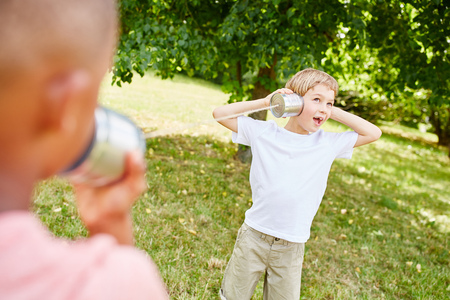 Two kids talking with tin can phone and playing in the parkの写真素材