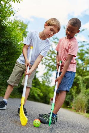 Two boys play street hockey together in the parkの写真素材