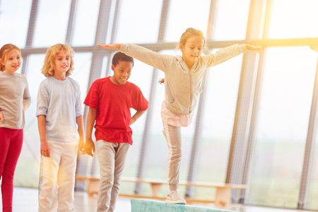 Girl doing gymnastics in gym class on the balance beamの写真素材