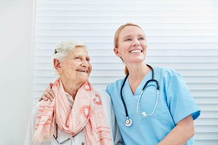 Smiling nursing woman with happy senior citizen