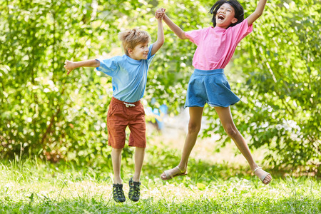 Boy and girl cheer together and jump into the air, laughingの写真素材