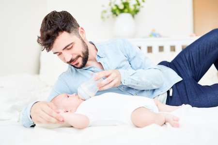 Loving father gives his baby the bottle with breast milk or baby milk
